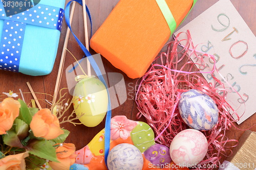 Image of Easter with eggs in nest and yellow tulips over blue wooden table. Top view