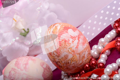 Image of Painted Easter eggs decorated with flowers with pearls in a basket on an old table