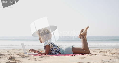 Image of Happy Woman Typing On A Laptop On A Beach