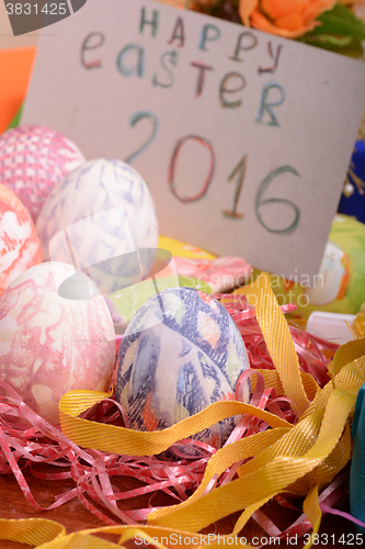 Image of Easter with eggs in nest and yellow tulips over blue wooden table. Top view