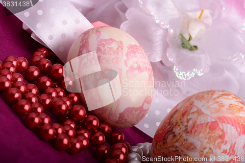 Image of Painted Easter eggs decorated with flowers with pearls in a basket on an old table