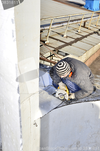 Image of Unidentified worker cutting sheet metal electric hand tool on th