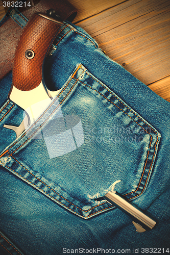 Image of silver revolver nagant with brown handle in the pocket