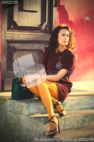 Image of woman in a burgundy dress sitting on the old porch