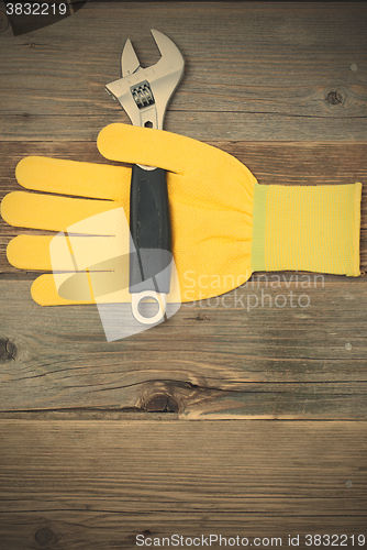 Image of yellow safety glove and a pipe wrench