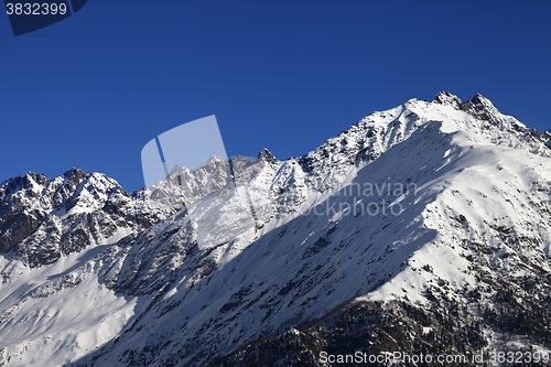 Image of Snowy rocks and blue clear sky at nice sun day
