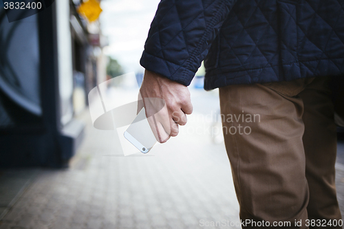 Image of Young men holding smartphone in hand on the street