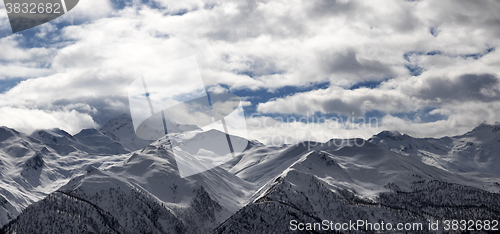 Image of Panoramic view on snowy mountains and cloudy sky in evening