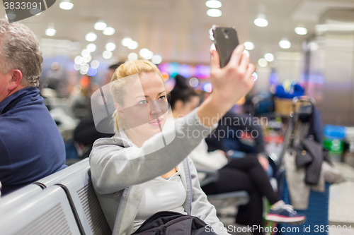 Image of Female traveler taking selfie on airport.