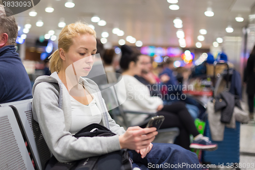 Image of Female traveler using cell phone while waiting.