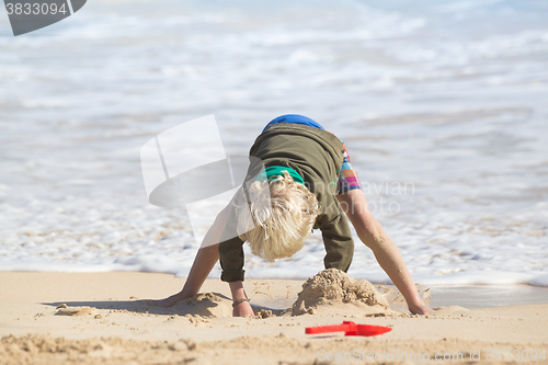 Image of Boy playing with toys on beach.