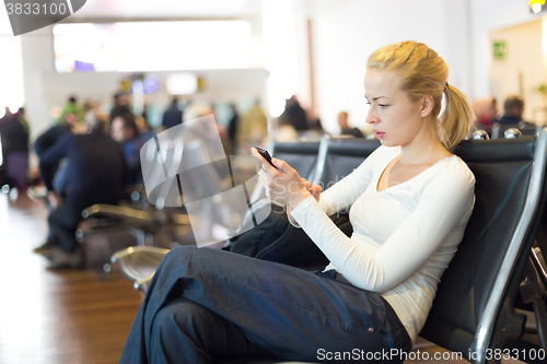 Image of Female traveler using cell phone while waiting.