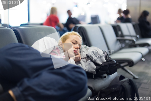 Image of Tired female traveler sleeping on airport.