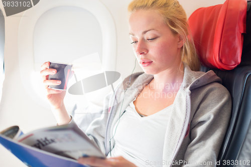 Image of Woman reading magazine on airplane.