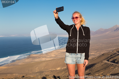 Image of Woman snaping holiday selfie on El Cofete beach