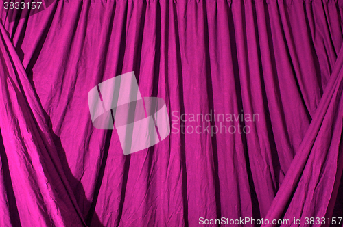Image of Draped black background cloth lit with pink gel
