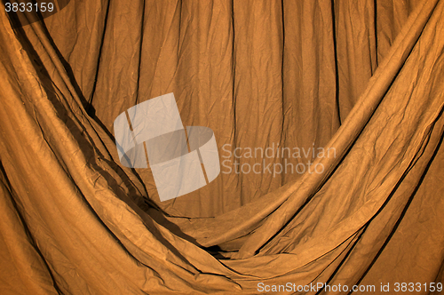 Image of Draped black background cloth lit with orange gel