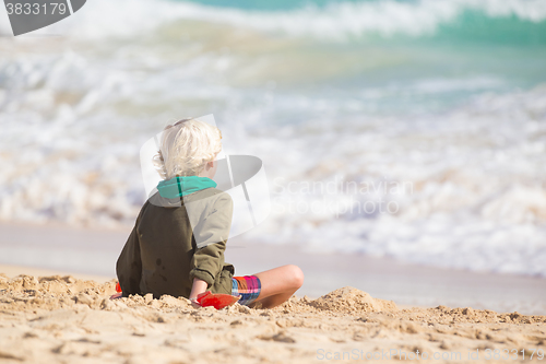 Image of Boy playing with toys on beach.