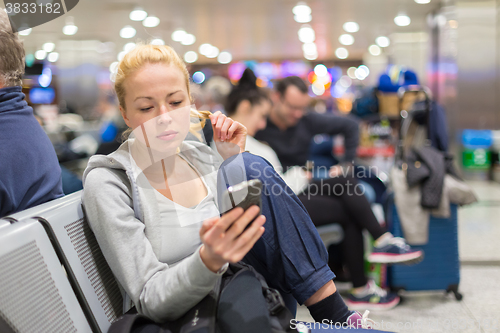 Image of Female traveler using cell phone while waiting.