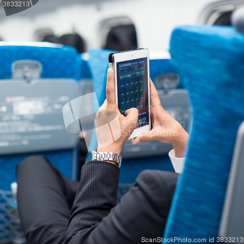 Image of Businessman using tablet phone on airplane.