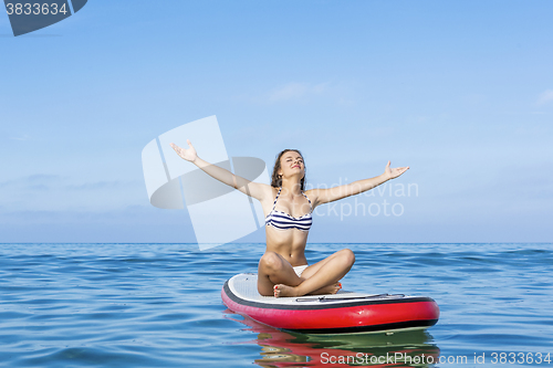 Image of Woman relaxing over a paddle surfboard