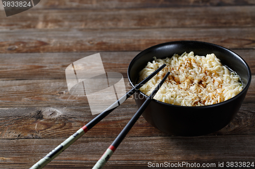 Image of bowl of noodles with vegetables on wood table