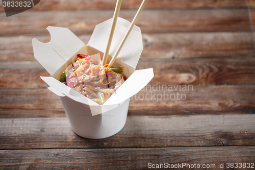 Image of Noodles with pork and vegetables in take-out box on wooden table