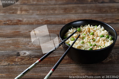 Image of bowl of noodles with vegetables on wood table