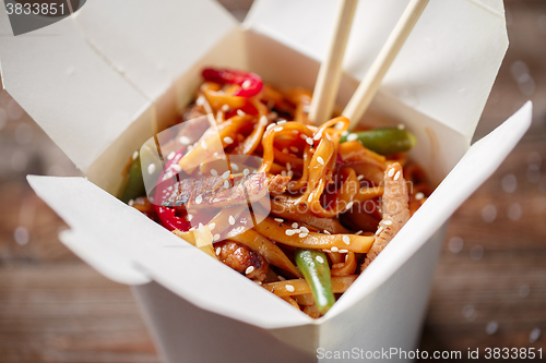 Image of Noodles with pork and vegetables in take-out box on wooden table