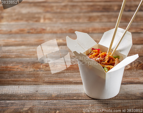 Image of Noodles with pork and vegetables in take-out box on wooden table