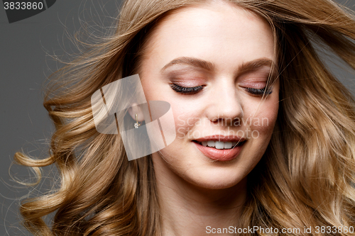 Image of Beautiful woman with long curly hair. Posing at studio.