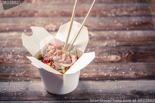 Image of Noodles with pork and vegetables in take-out box on wooden table