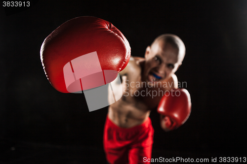 Image of The young man kickboxing on black  with kapa in mouth