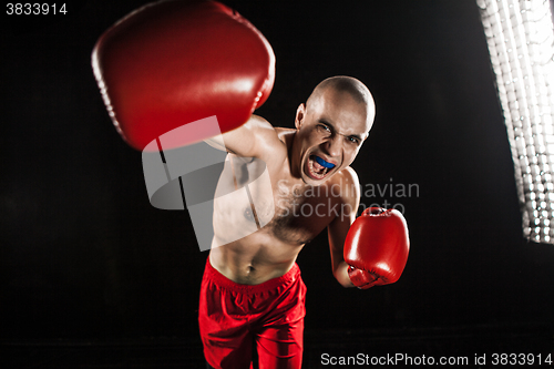 Image of The young man kickboxing on black  with kapa in mouth