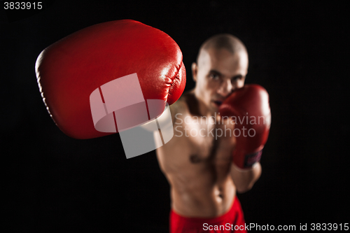 Image of The young man kickboxing on black  with kapa in mouth