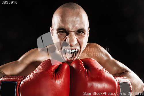 Image of The young man kickboxing on black  with kapa in mouth