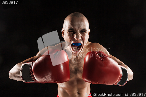 Image of The young man kickboxing on black  with kapa in mouth