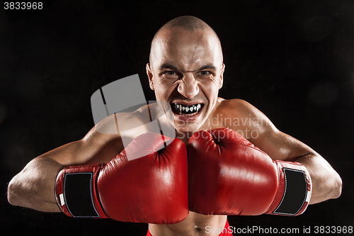 Image of The young man kickboxing on black  with kapa in mouth