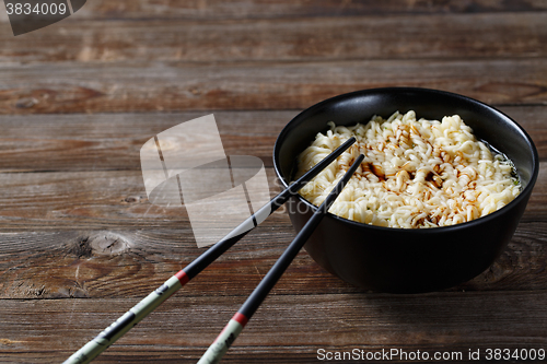 Image of bowl of noodles with vegetables on wood table