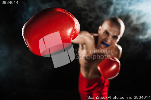 Image of The young man kickboxing on black  with kapa in mouth