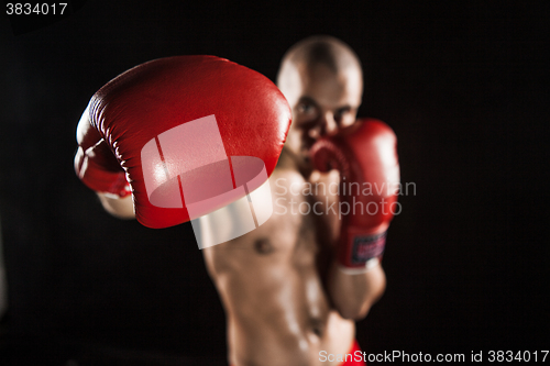 Image of The young man kickboxing on black