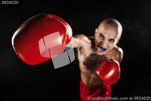 Image of The young man kickboxing on black  with kapa in mouth