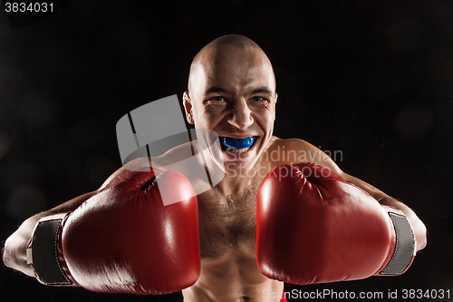 Image of The young man kickboxing on black  with kapa in mouth