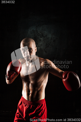 Image of The young man kickboxing on black