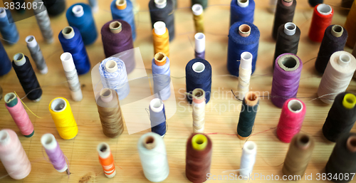 Image of Sewing threads arranged on wooden board
