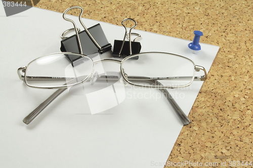 Image of spectacles and bulldog clips on paper