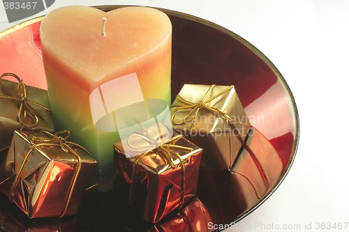 Image of heart candle and presents in a red glass bowl