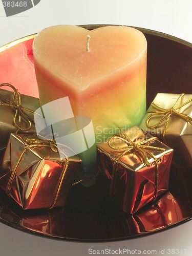 Image of heart candle and presents in a red glass bowl