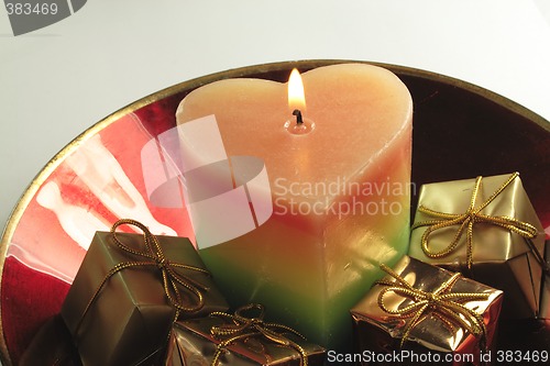 Image of heart candle and presents in a red glass bowl