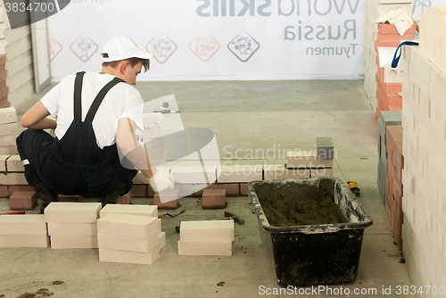 Image of Young bricklayer performs a task of competition